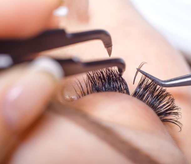 Eyelash extensions application with tweezers.